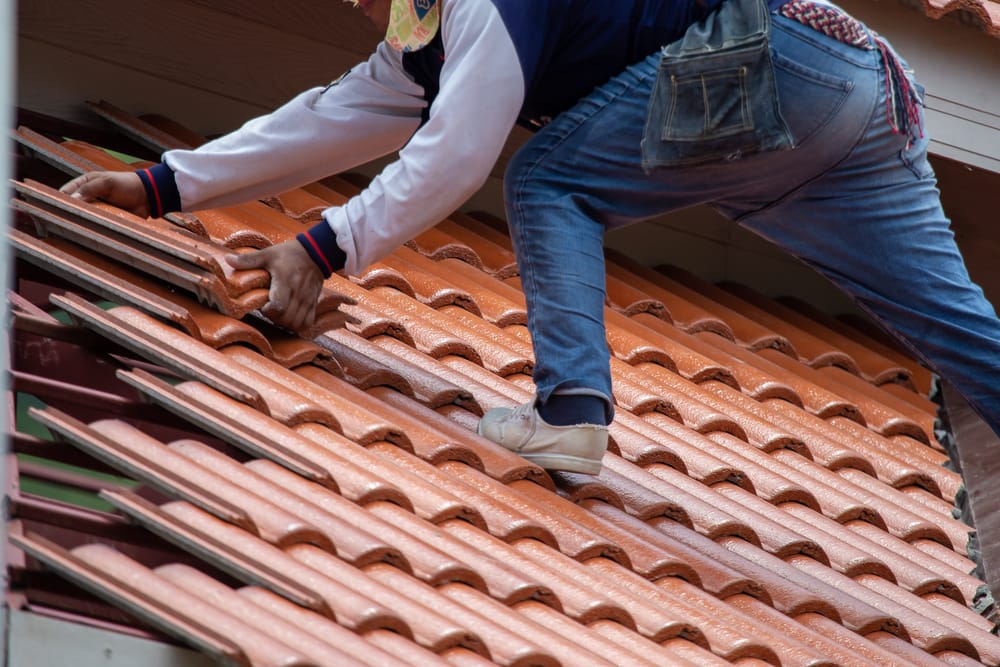 A person on a roof working on insulation batts